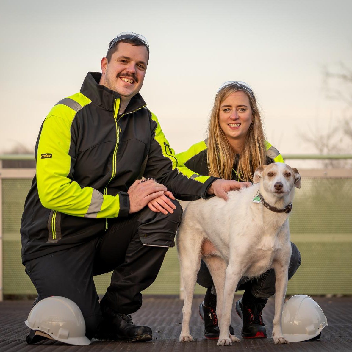 Zwei Personen in Arbeitskleidung mit einem Hund auf einem Außengelände. Julia Zoonz Alexander Zoonz